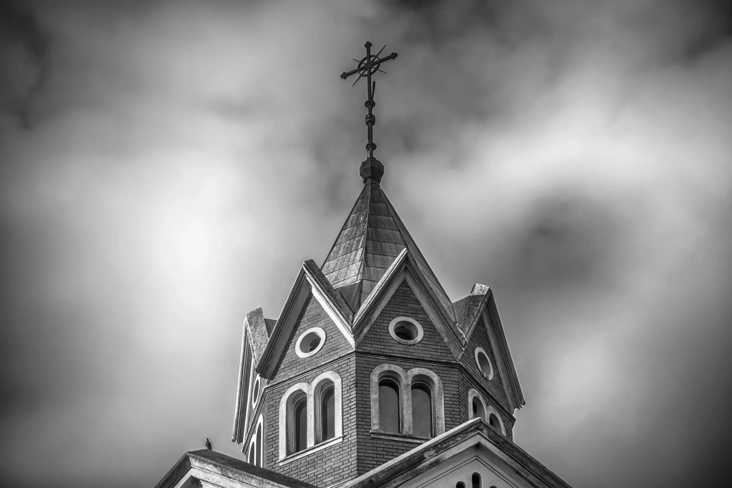 low-angle-greyscale-shot-top-christian-church-with-cloudy-sky-min